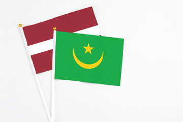 Mauritania and Latvia stick flags on white background. High quality fabric, miniature national flag. Peaceful global concept.White floor for copy space.