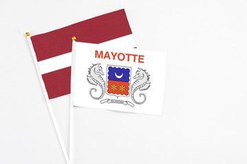 Mayotte and Latvia stick flags on white background. High quality fabric, miniature national flag. Peaceful global concept.White floor for copy space.