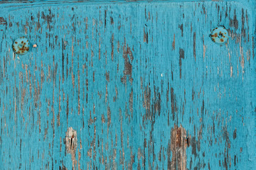 Old wooden surface with peeling paint. Blue grunge background with scratches and nails