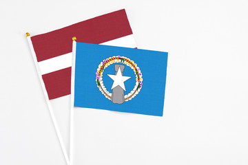 Northern Mariana Islands and Latvia stick flags on white background. High quality fabric, miniature national flag. Peaceful global concept.White floor for copy space.