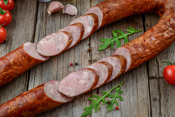 Salami sausages sliced with pepper, garlic and rosemary on cutting board