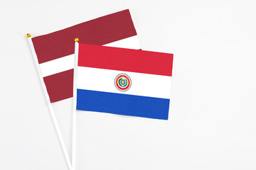 Paraguay and Latvia stick flags on white background. High quality fabric, miniature national flag. Peaceful global concept.White floor for copy space.