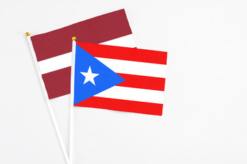 Puerto Rico and Latvia stick flags on white background. High quality fabric, miniature national flag. Peaceful global concept.White floor for copy space.