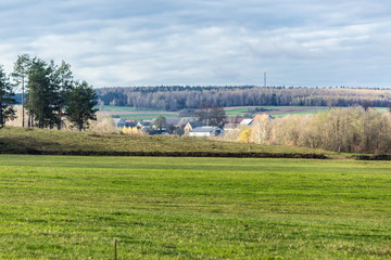 A village among fields and pastures. Green meadow in the foreground. Late autumn in Podlasie, Poland.