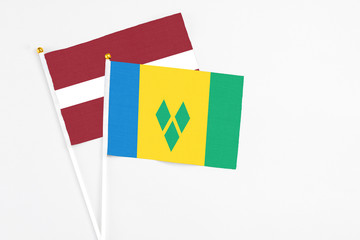 Saint Vincent And The Grenadines and Latvia stick flags on white background. High quality fabric,...