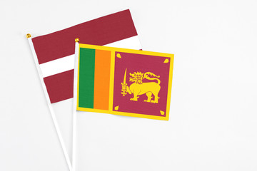 Sri Lanka and Latvia stick flags on white background. High quality fabric, miniature national flag. Peaceful global concept.White floor for copy space.