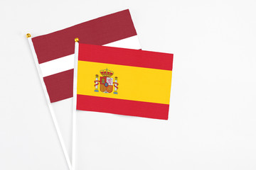 Spain and Latvia stick flags on white background. High quality fabric, miniature national flag. Peaceful global concept.White floor for copy space.