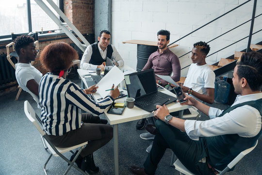 Businessmen of different nationalities are talking at a round table in a modern office