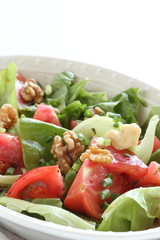 Tomato and walnut salad on white background with copy space