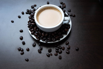 Roasted coffee beans that have not been thoroughly ground in a white ceramic glass placed on a black table with small tree for decoration. Cut frame to square, window light, flat layout, vintage tone 
