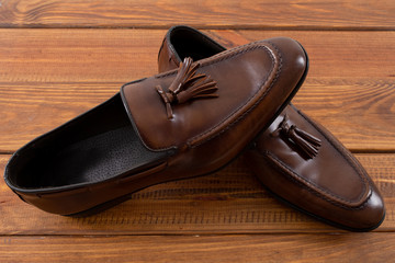 Brown classic loafers with tassels stand on a wooden stand