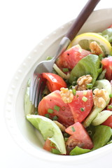 Tomato and walnut salad on white background with copy space
