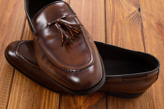 Brown classic loafers with tassels stand on a wooden stand