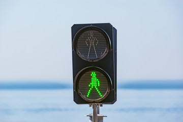 The green light of traffic light on the pedestrian railway crossing of a human silhouette.