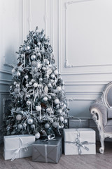 Modern decorated Christmas tree in white and silver colors with gift boxes