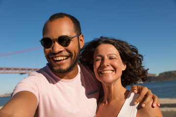 Young couple smiling at camera. Portrait of beautiful multiethnic man and woman standing together near river and smiling at camera. Emotion concept