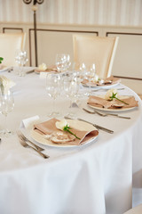 Table setting with blank guest card, white plate with beige serviette, rose, heart and cutlery on table, copy space. Place setting at wedding reception. Table served for wedding banquet in restaurant