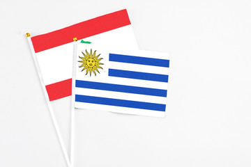 Uruguay and Lebanon stick flags on white background. High quality fabric, miniature national flag. Peaceful global concept.White floor for copy space.