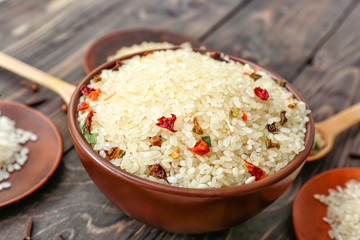 Bowl with raw rice and dry vegetables on wooden table