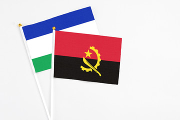 Angola and Lesotho stick flags on white background. High quality fabric, miniature national flag. Peaceful global concept.White floor for copy space.