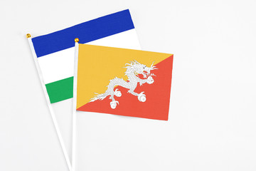 Bhutan and Lesotho stick flags on white background. High quality fabric, miniature national flag. Peaceful global concept.White floor for copy space.