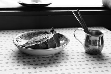 Tarta de chocolate con azucarero sobre mesa en blanco y negro