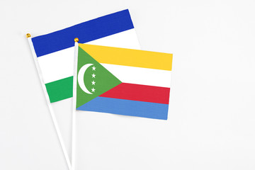 Comoros and Lesotho stick flags on white background. High quality fabric, miniature national flag. Peaceful global concept.White floor for copy space.