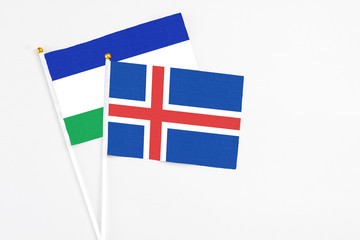 Iceland and Lesotho stick flags on white background. High quality fabric, miniature national flag. Peaceful global concept.White floor for copy space.