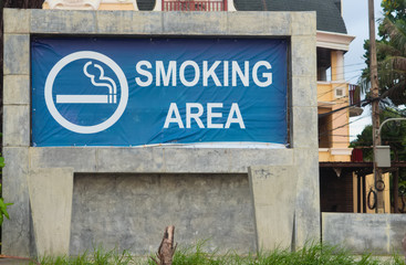 A large sign indicating a Smoking area, with two stone ashtrays