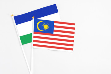 Malaysia and Lesotho stick flags on white background. High quality fabric, miniature national flag. Peaceful global concept.White floor for copy space.
