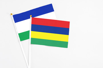 Mauritius and Lesotho stick flags on white background. High quality fabric, miniature national flag. Peaceful global concept.White floor for copy space.