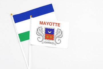 Mayotte and Lesotho stick flags on white background. High quality fabric, miniature national flag. Peaceful global concept.White floor for copy space.