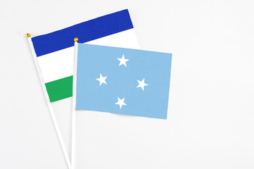 Micronesia and Lesotho stick flags on white background. High quality fabric, miniature national flag. Peaceful global concept.White floor for copy space.