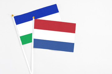 Netherlands and Lesotho stick flags on white background. High quality fabric, miniature national flag. Peaceful global concept.White floor for copy space.