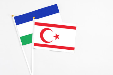 Northern Cyprus and Lesotho stick flags on white background. High quality fabric, miniature national flag. Peaceful global concept.White floor for copy space.