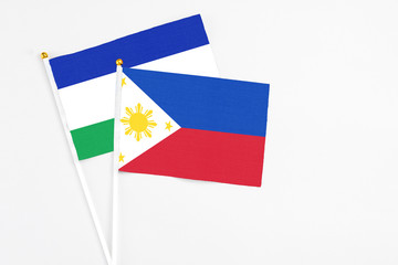 Philippines and Lesotho stick flags on white background. High quality fabric, miniature national flag. Peaceful global concept.White floor for copy space.