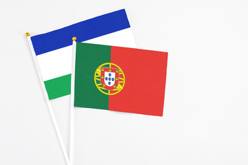 Portugal and Lesotho stick flags on white background. High quality fabric, miniature national flag. Peaceful global concept.White floor for copy space.