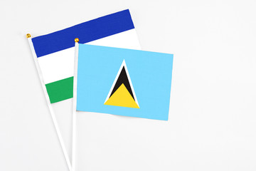 Saint Lucia and Lesotho stick flags on white background. High quality fabric, miniature national flag. Peaceful global concept.White floor for copy space.