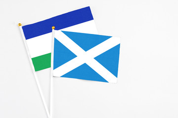 Scotland and Lesotho stick flags on white background. High quality fabric, miniature national flag. Peaceful global concept.White floor for copy space.
