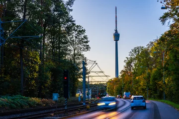 Deutschland, Stadtbild der Stuttgarter Stadtstraße mit Verkehr am Fernsehturmgebäude bei Sonnenuntergang, geschmückt mit bunten Herbstlaubbäumen © Simon Dux Media