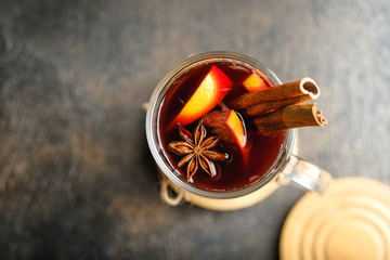 Mulled wine in glass with apples, orange, cinnamon and star anise. Hot Christmas drink on a dark background with a fir branch.