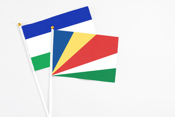 Seychelles and Lesotho stick flags on white background. High quality fabric, miniature national flag. Peaceful global concept.White floor for copy space.