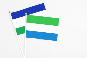 Sierra Leone and Lesotho stick flags on white background. High quality fabric, miniature national flag. Peaceful global concept.White floor for copy space.