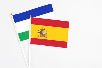 Spain and Lesotho stick flags on white background. High quality fabric, miniature national flag. Peaceful global concept.White floor for copy space.
