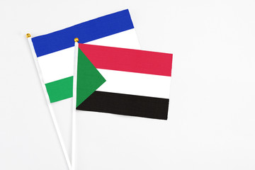 Sudan and Lesotho stick flags on white background. High quality fabric, miniature national flag. Peaceful global concept.White floor for copy space.