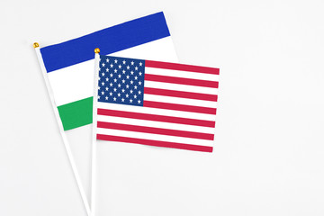 United States and Lesotho stick flags on white background. High quality fabric, miniature national flag. Peaceful global concept.White floor for copy space.