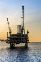 Fototapeta premium Silhouette of oil production platform during sunset at oil field