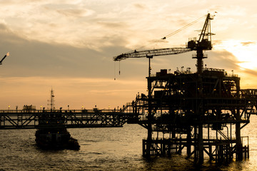 Silhouette of oil production platform during sunset at oil field