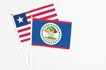 Belize and Liberia stick flags on white background. High quality fabric, miniature national flag. Peaceful global concept.White floor for copy space.