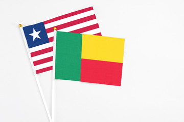 Benin and Liberia stick flags on white background. High quality fabric, miniature national flag. Peaceful global concept.White floor for copy space.